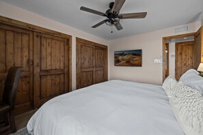 A bedroom with a large bed, wooden wardrobe, a ceiling fan, and a painting on the wall. - The Villa at Fountain Hills | Pool, Hot Tub, Game Room, Ping Pong & Sleeps 20 (Fountain Hills)