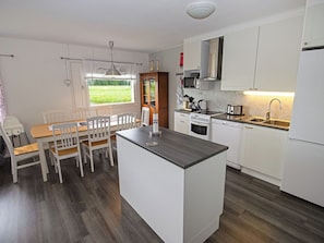 A compact kitchen with white cabinets, a central island, a microwave, stove, and dishwasher.