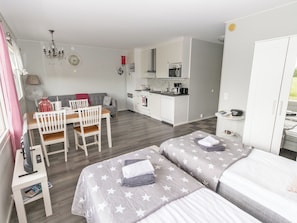 A compact room with a kitchenette, a dining area, and two beds with star-patterned bedding.