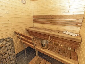 A sauna with wooden benches, a metal bucket, and a stone-filled container labeled 'HARVIA'. - Vacation home Tupa by Interhome (Juva)