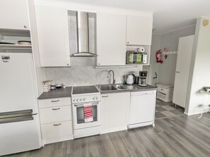 A modern kitchen with white cabinetry, a stainless steel range hood, a built-in microwave, and a coffee maker. - Vacation home Tupa by Interhome (Juva)