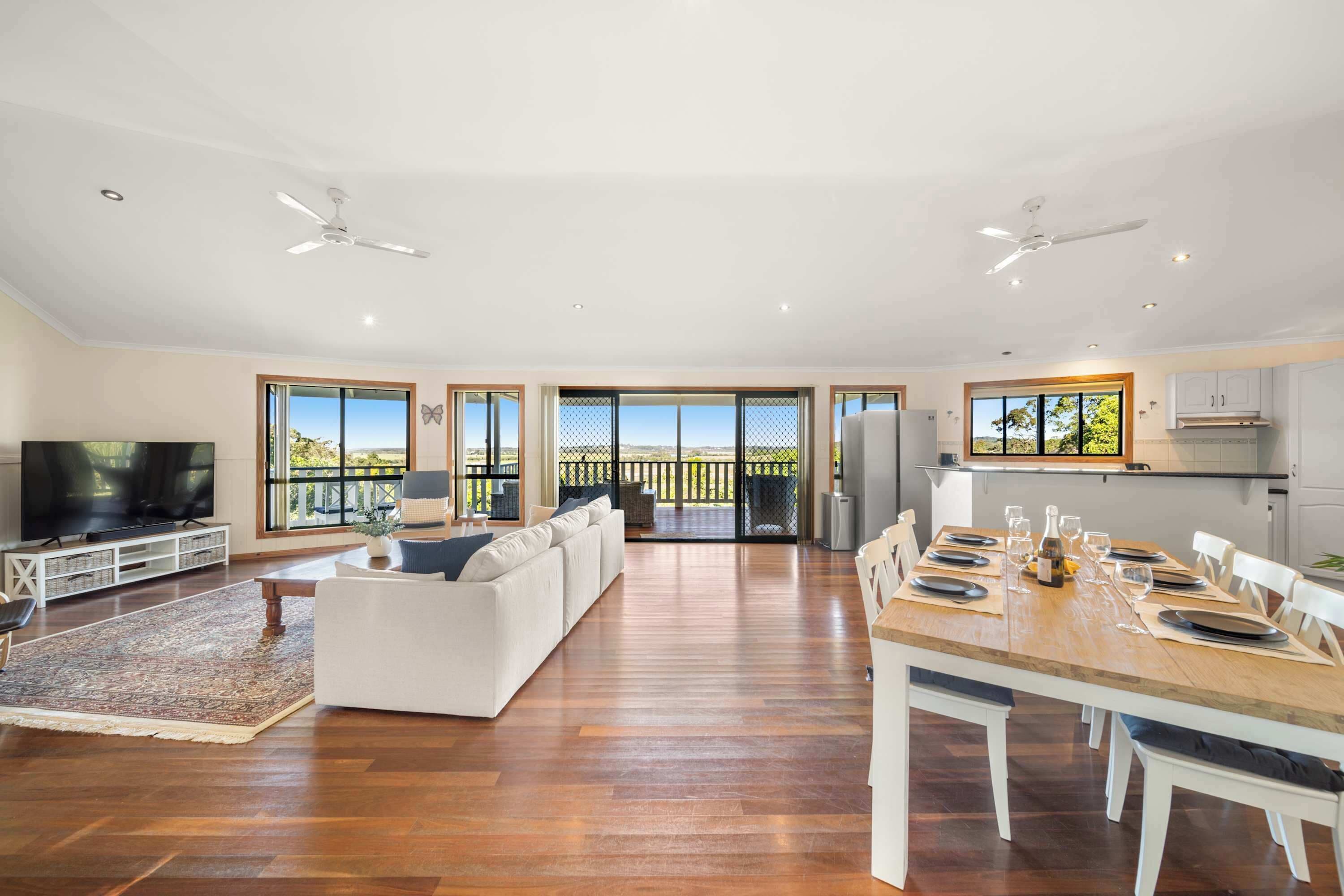Gather around the timber dining table for shared meals and lively conversation, with the open-plan layout keeping everyone connected while leafy views provide a peaceful backdrop.