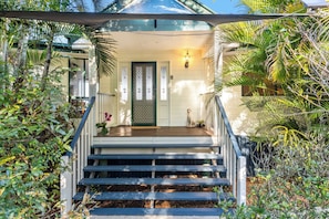 Ein Haus mit Veranda, Treppe und einer Tür mit dekorativem Glasfenster.