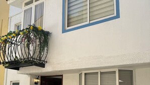 Een tweelaags huis met een balkon, een voordeur en een raam met luiken.