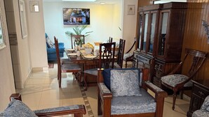 Een woonkamer met een bank, stoelen, een salontafel en een televisie.
