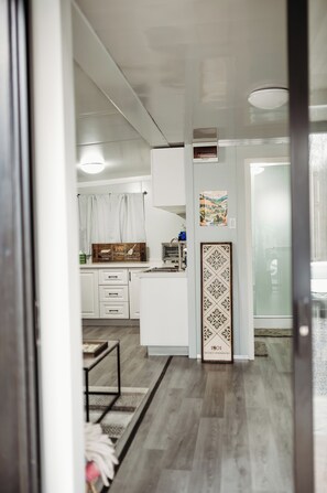 Una cocina moderna con armarios blancos, encimera de madera y un panel decorativo.