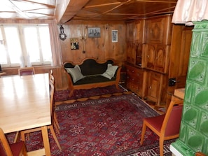 Ein Zimmer mit einer Holzsofa, einem Esstisch, Stühlen, einem gemusterten Teppich und Holzschränken.