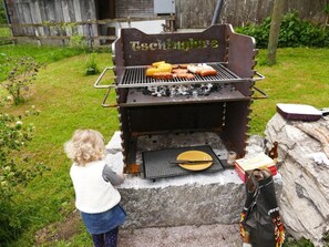 Ein Kind steht neben einem Grill mit Essen darauf.