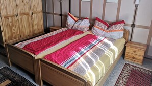 Un lit en bois avec une couvre-lit à motifs, une table de chevet, une armoire en bois et un mur orné de tableaux encadrés.
