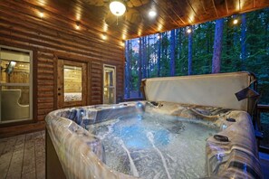 Una banyera d'hidromassatge en una cabana de fusta amb vistes a un bosc.