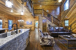Ein Holzhaus-Interieur mit einer Steinarbeitsplatte, einem Ledersofa, einer Treppe und einem Essbereich.
