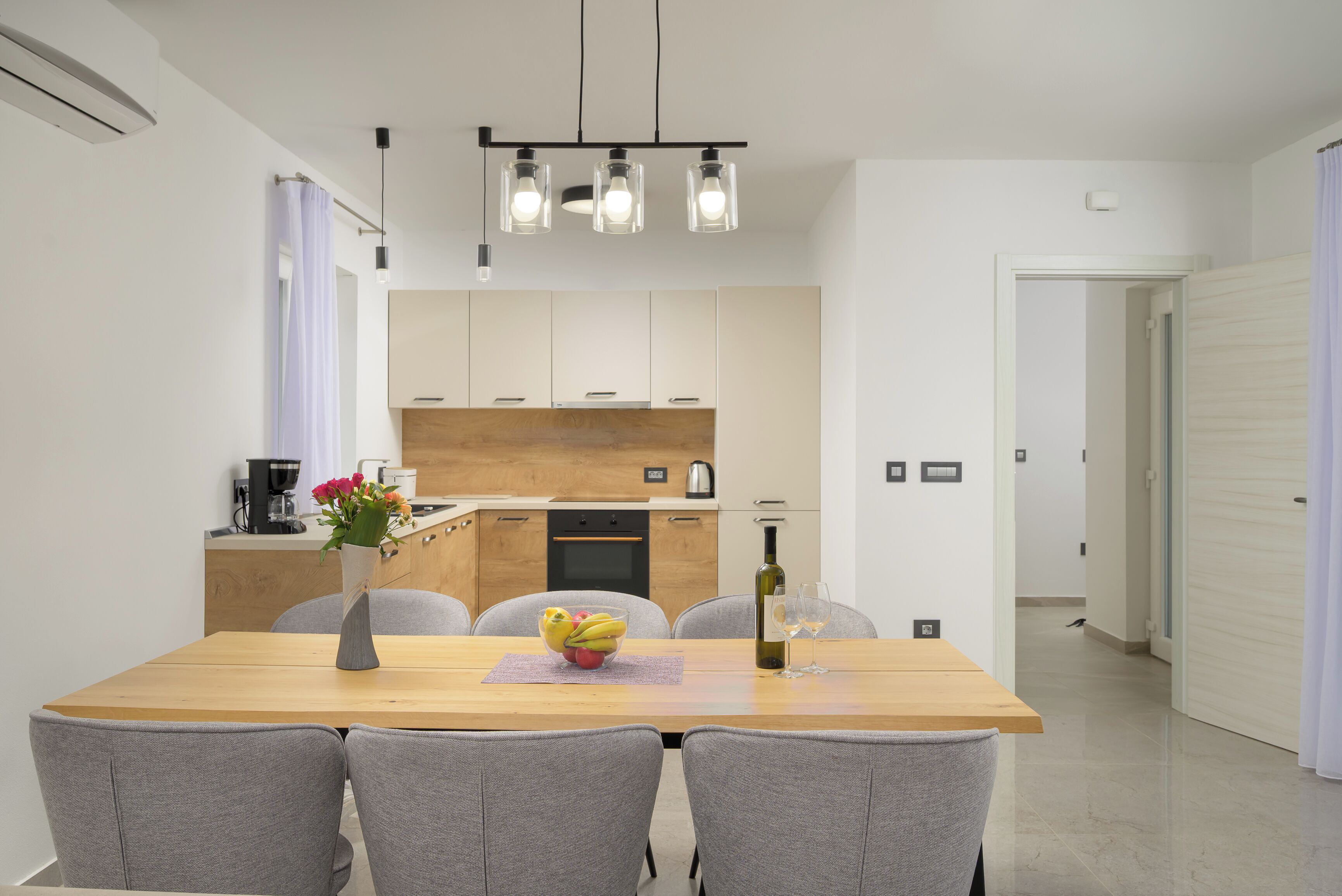 A modern kitchen with white cabinets, a wooden countertop, and a dining area with a table and chairs.