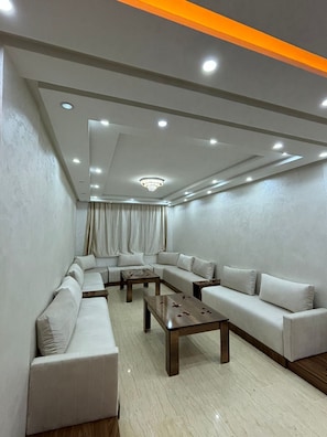 A modern living room with a sectional sofa, a coffee table, and recessed lighting. - Apartment center Gueliz (Marrakech)