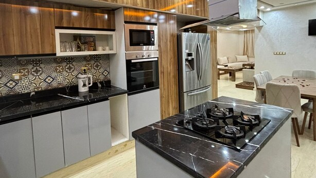 Eine moderne Küche mit einer zentralen Kochinsel, eingebautem Backofen, Mikrowelle und einem Edelstahl-Kühlschrank.