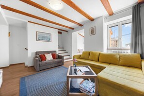 Ett vardagsrum med en soffa, ett soffbord och en trappa som leder till ett annat rum.