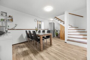 Eine moderne Küche mit Essbereich, Holzboden und einer Treppe.