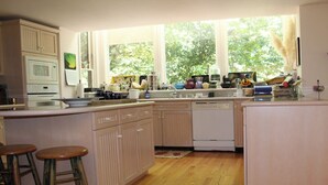 A kitchen with wooden cabinets, a microwave, a dishwasher, and a window with a view of trees. - Tranquil Country Estate with Fantastic Garden (Glen Ellen)