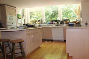 Eine Küche mit Holzschränken, einer Mikrowelle, einem Geschirrspüler und einem Fenster mit Blick auf Bäume.