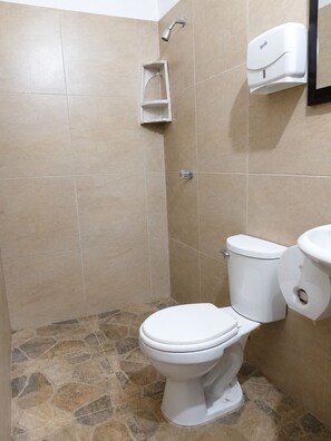 Een douche, handdoeken, zeep, toiletpapier