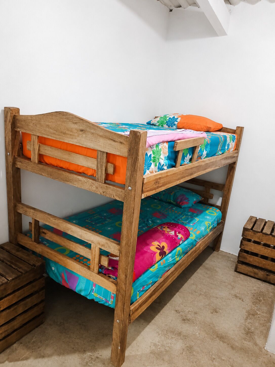 A bunk bed with colorful bedding and wooden headboard.