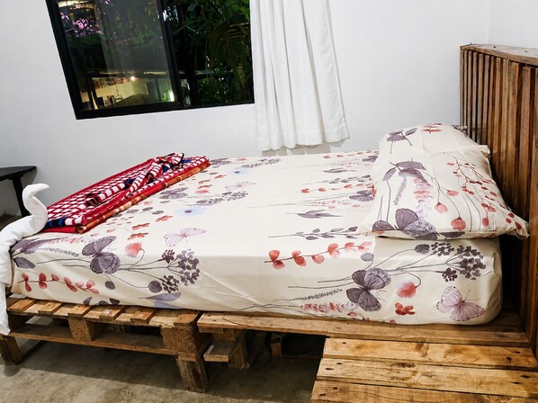 A bed with a floral bedspread, a pillow with a similar design, and a red and white striped blanket.