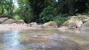 Un corpo d'acqua naturale circondato da rocce e fitta vegetazione.