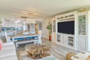 A modern living room with a dining area, white cabinetry, and a flat-screen TV. - Luxurious Oceanfront Condo, Amazing Ocean Sunrise and Intercoastal Sunset Views, Steps to Sand, Pool (St. Augustine)