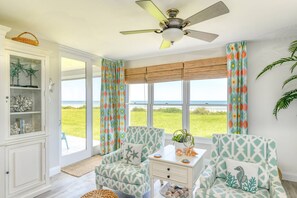 A room with a ceiling fan, two patterned armchairs, a white side table, and a view of the ocean. - Luxurious Oceanfront Condo, Amazing Ocean Sunrise and Intercoastal Sunset Views, Steps to Sand, Pool (St. Augustine)