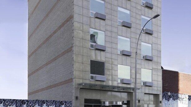 Un edificio a più piani dal design moderno, caratterizzato da un tetto piano, ampie finestre e un ingresso ben visibile con una porta in vetro.