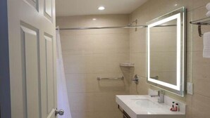 Un bagno con il water, un lavandino, uno specchio, una doccia e una porta.