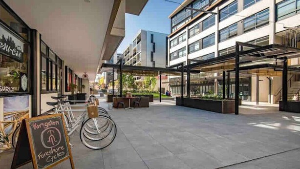 A modern building with a covered outdoor area, bicycles, and a sign for 'Kingston Foresight Cycles.' - The Barty by Parbery Property (Kingston)