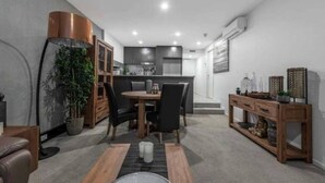 A modern kitchen with a dining area, a wooden console table, and a potted plant. - The Barty by Parbery Property (Kingston)
