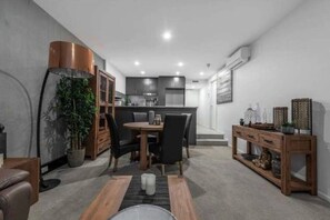 Eine moderne Küche mit Essbereich, einem Holztischchen und einem Topf mit Pflanze.