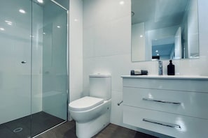 Ein modernes Badezimmer mit Duschkabine aus Glas, Toilette und Waschtisch mit Spiegel.