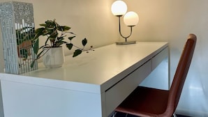 Ett modernt skrivbord med en krukväxt, en dekorativ metallskulptur och en lampa.