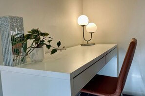 Ein moderner Schreibtisch mit Zimmerpflanze, einem dekorativen Metallkunstwerk und einer Lampe.
