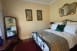 Un dormitorio con una cama, un espejo, dos cuadros en la pared y una alfombra roja.