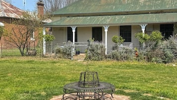 Ein Haus mit Veranda, Rasen und einem Metalltisch im Vordergrund.