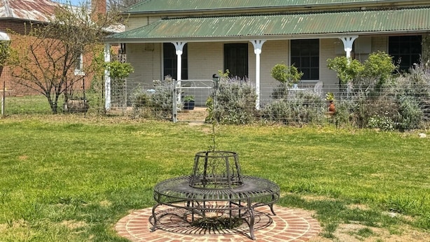 A house with a porch, a lawn, and a metal table in the foreground.