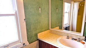 Ein Badezimmer mit einem weißen Waschbecken, einem Spiegel und einer grünen Wand.