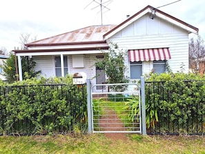 A two-story house with a metal gate, a small garden, and a mailbox.