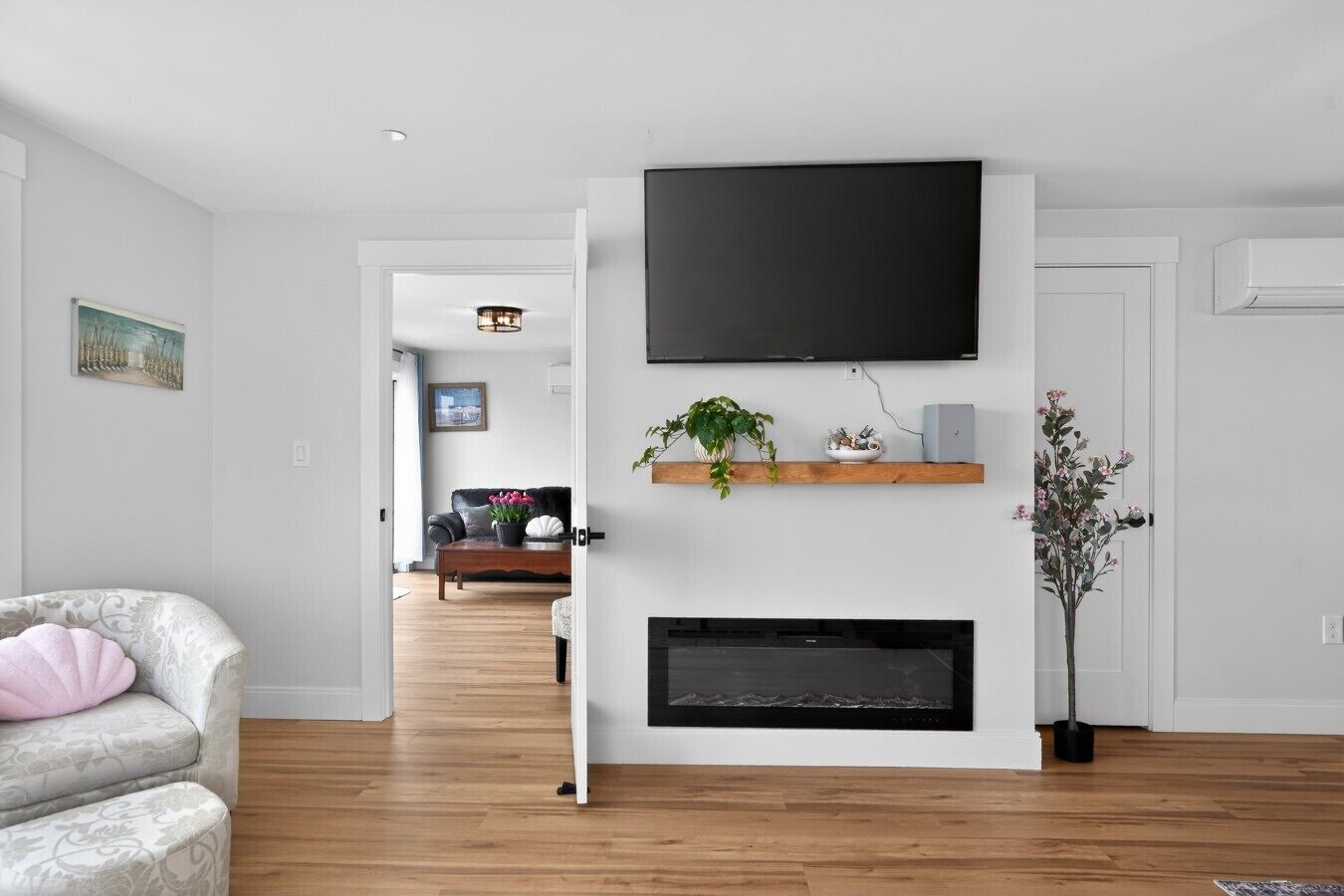 A modern living room with a fireplace, a mounted TV, and a wooden coffee table.