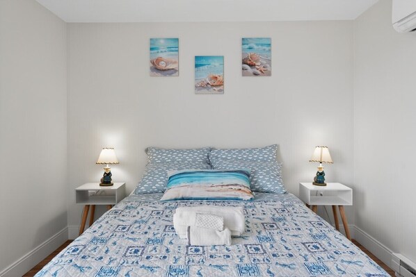 A bedroom with a bed, two bedside tables, and three wall-mounted pictures.