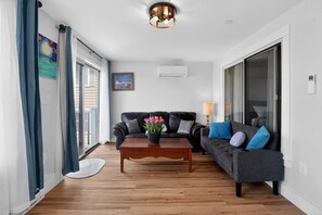 A living room with a sofa, a coffee table with flowers, a lamp, and a painting on the wall.