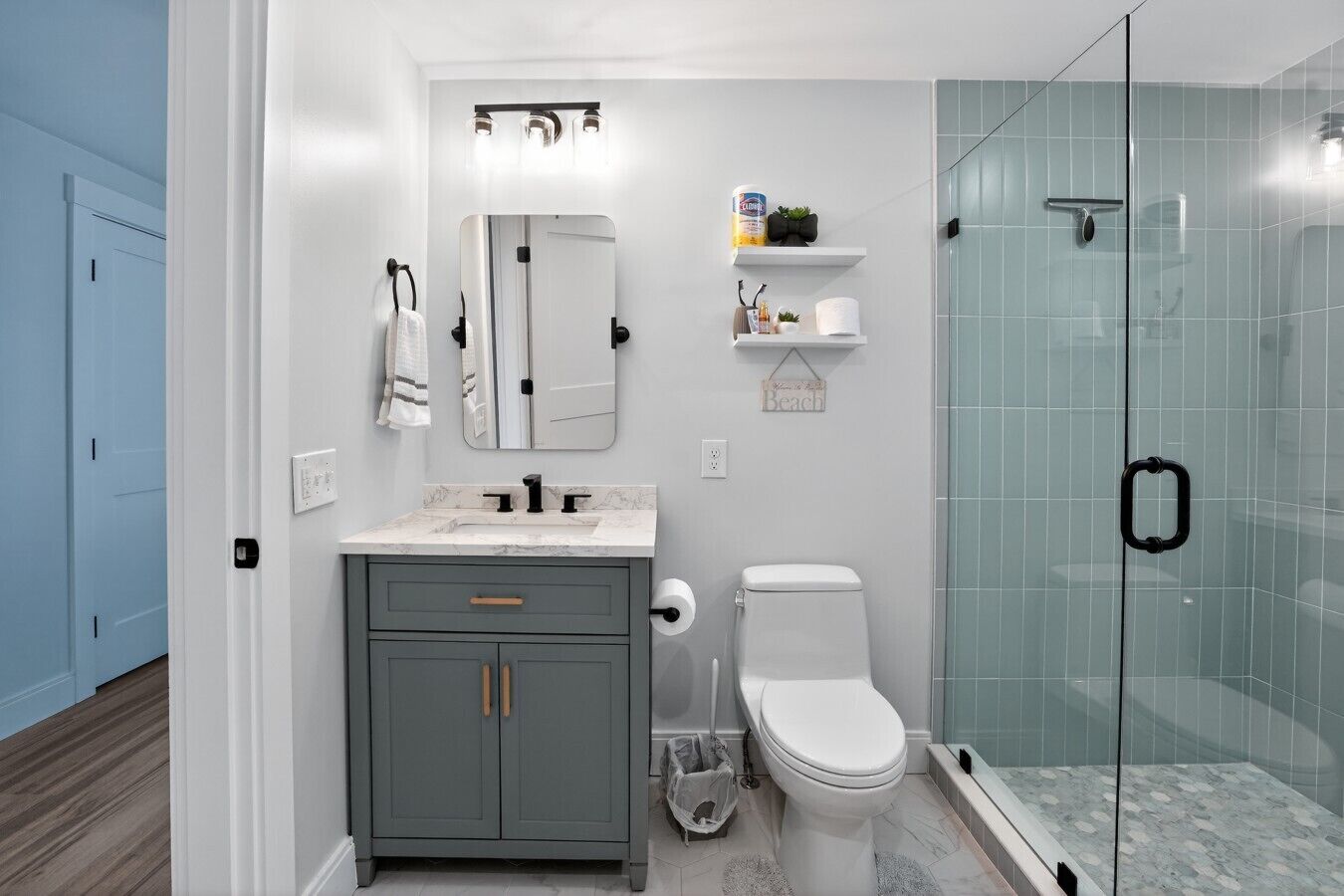 A bathroom with a shower, a toilet, a sink, and a mirror.