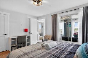 A bedroom with a bed, a desk, a chair, and a window with curtains.