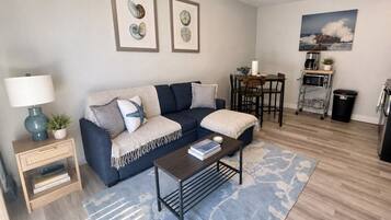 A living room with a sofa, coffee table, and a dining area with a table and chairs.