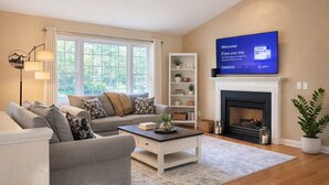 A living room with a sofa, a coffee table, a fireplace, a TV, and a bookshelf. - Sleep up to 12, quick access to Kittery and Portsmouth, Beaches, Boat Launch (Eliot)