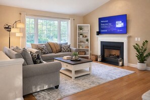 Una sala de estar con sofá, mesa de centro, chimenea, televisor y estantería.