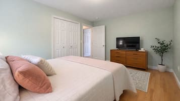 Un dormitorio con una cama, un aparador, un televisor y una planta en maceta.